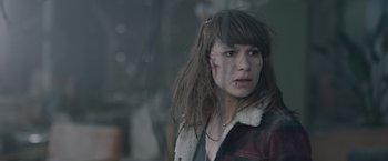 Movie still from “The Quake” (2018), directed by John Andreas Andersen – A young woman with brown hair and a brown and white jacket; Close Up shot, Over the shoulder angle
