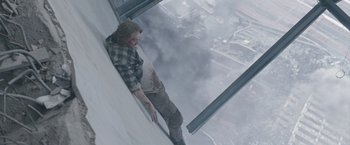 Movie still from “The Quake” (2018), directed by John Andreas Andersen – A man leans against a ledge on the side of a skyscraper; Wide shot, Overhead angle