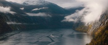 Movie still from “The Quake” (2018), directed by John Andreas Andersen – A body of water surrounded by mountains and clouds; Extreme Wide shot, High angle