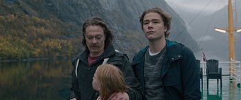 Movie still from “The Quake” (2018), directed by John Andreas Andersen – Two men and a little girl standing next to each other in front of a mountain; Medium shot, Low angle