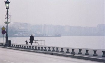 Movie still from “Eternity and a Day” (1998), directed by Theodoros Angelopoulos – A man sitting on a bench next to the water; Extreme Wide shot, High angle