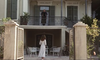 Movie still from “Eternity and a Day” (1998), directed by Theodoros Angelopoulos – A woman standing on a balcony looking at a man; Wide shot, Low angle