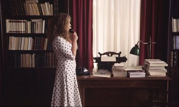 Movie still from “Eternity and a Day” (1998), directed by Theodoros Angelopoulos – A woman standing in front of a desk talking on a phone; Wide shot, High angle