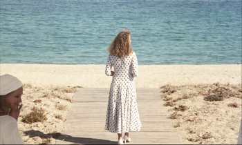 Movie still from “Eternity and a Day” (1998), directed by Theodoros Angelopoulos – A woman in a polka dot dress standing on a beach; Wide shot, High angle