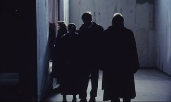 Movie still from “Eternity and a Day” (1998), directed by Theodoros Angelopoulos – A group of people standing in a dark room; Wide shot, High angle