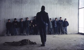 Movie still from “Eternity and a Day” (1998), directed by Theodoros Angelopoulos – A group of people standing in front of a concrete wall; Wide shot, Low angle