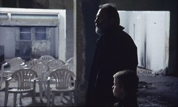 Movie still from “Eternity and a Day” (1998), directed by Theodoros Angelopoulos – An older man and a young boy standing next to each other; Medium shot, Over the shoulder angle