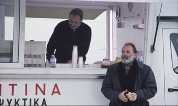 Movie still from “Eternity and a Day” (1998), directed by Theodoros Angelopoulos – A man standing in front of a food truck; Medium shot, Low angle