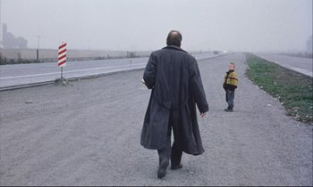 Movie still from “Eternity and a Day” (1998), directed by Theodoros Angelopoulos – A man and a child walking down a road; Wide shot, Over the shoulder angle