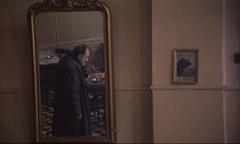 Movie still from “Eternity and a Day” (1998), directed by Theodoros Angelopoulos – A man standing in front of a mirror taking a picture of himself; Wide shot, Over the shoulder angle