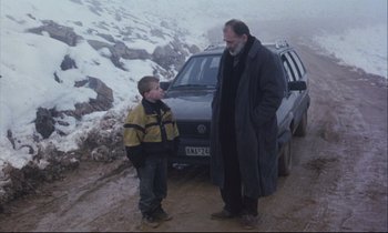Movie still from “Eternity and a Day” (1998), directed by Theodoros Angelopoulos – A man standing next to a car with a boy; Wide shot, Over the shoulder angle