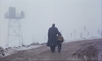 Movie still from “Eternity and a Day” (1998), directed by Theodoros Angelopoulos – A man and a child walking on a dirt road in the snow; Wide shot, Low angle