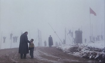 Movie still from “Eternity and a Day” (1998), directed by Theodoros Angelopoulos – A man and a child standing on the side of a road in the snow; Wide shot, Low angle