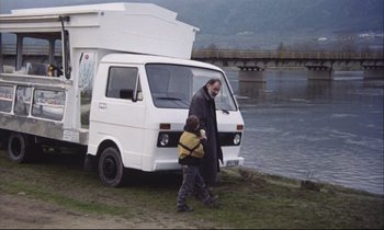Movie still from “Eternity and a Day” (1998), directed by Theodoros Angelopoulos – A man and a boy walking next to an rv; Wide shot, Low angle