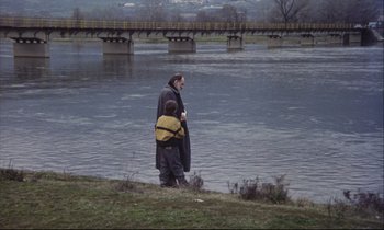 Movie still from “Eternity and a Day” (1998), directed by Theodoros Angelopoulos – A man and a child standing on the bank of a river; Wide shot, High angle