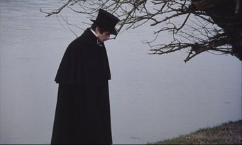 Movie still from “Eternity and a Day” (1998), directed by Theodoros Angelopoulos – A man wearing a black coat and a black hat; Medium shot, High angle