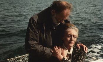 Movie still from “Eternity and a Day” (1998), directed by Theodoros Angelopoulos – An older man standing next to an older woman on a boat; Medium shot, High angle