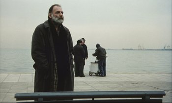 Movie still from “Eternity and a Day” (1998), directed by Theodoros Angelopoulos – A group of people standing on a pier near the water; Medium shot, Low angle