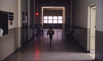 Movie still from “Eternity and a Day” (1998), directed by Theodoros Angelopoulos – A person is walking down a hallway in a building; Extreme Wide shot, Low angle