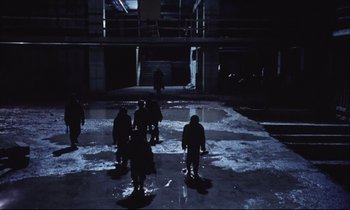 Movie still from “Eternity and a Day” (1998), directed by Theodoros Angelopoulos – A group of snowboarders standing in a parking garage; Wide shot, High angle