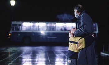 Movie still from “Eternity and a Day” (1998), directed by Theodoros Angelopoulos – A man standing next to a bus at night; Wide shot, Low angle