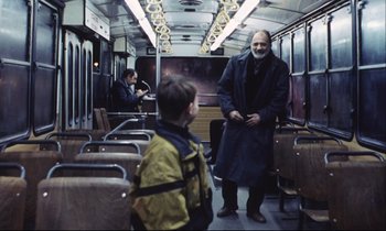 Movie still from “Eternity and a Day” (1998), directed by Theodoros Angelopoulos – A man standing on a train with a child in the background; Medium shot, Over the shoulder angle