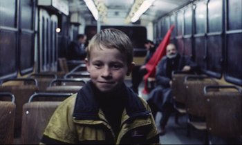 Movie still from “Eternity and a Day” (1998), directed by Theodoros Angelopoulos – A young boy sitting on a train with a red umbrella; Medium shot, Low angle