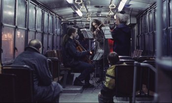 Movie still from “Eternity and a Day” (1998), directed by Theodoros Angelopoulos – A group of people riding on a train with musical instruments; Wide shot, Low angle