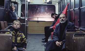 Movie still from “Eternity and a Day” (1998), directed by Theodoros Angelopoulos – A group of people sitting on a train; Medium shot, High angle