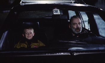Movie still from “Eternity and a Day” (1998), directed by Theodoros Angelopoulos – A man and a boy sitting in the back seat of a car; Medium shot, Low angle