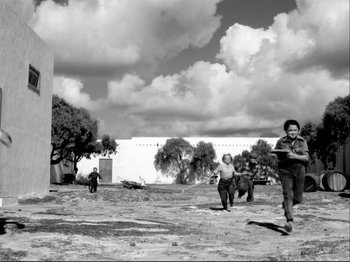 Movie still from “Even Dwarfs Started Small” (1970), directed by Werner Herzog – A black and white photo of people playing frisbee; Extreme Wide shot, Low angle