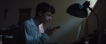 Movie still from “Every Day” (2018), directed by Michael Sucsy – A young man holding a cell phone in his hands; Close Up shot, Low angle