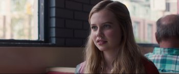 Movie still from “Every Day” (2018), directed by Michael Sucsy – A beautiful young lady sitting in front of a brick wall; Close Up shot, Over the shoulder angle