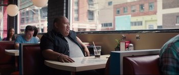 Movie still from “Every Day” (2018), directed by Michael Sucsy – A man sitting at a table in front of a glass of water; Medium shot, Over the shoulder angle