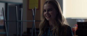 Movie still from “Every Day” (2018), directed by Michael Sucsy – A young girl smiles brightly while sitting in a classroom; Close Up shot, Over the shoulder angle