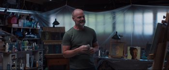 Movie still from “Every Day” (2018), directed by Michael Sucsy – A man standing in a room holding a remote control; Medium shot, Over the shoulder angle