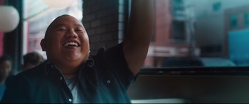 Movie still from “Every Day” (2018), directed by Michael Sucsy – A man with a smile on his face and his arms raised in the air; Close Up shot, Low angle