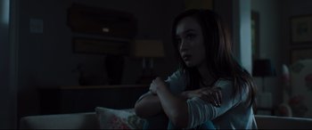Movie still from “Every Day” (2018), directed by Michael Sucsy – A young woman sitting on a couch in a dark room; Medium shot, Low angle