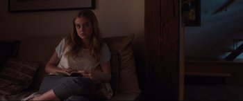Movie still from “Every Day” (2018), directed by Michael Sucsy – A woman sitting on a couch holding a remote control; Medium shot, Over the shoulder angle