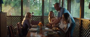 Movie still from “Every Day” (2018), directed by Michael Sucsy – A group of people sitting at a table with plates of food; Medium shot, Over the shoulder angle