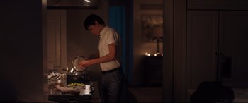 Movie still from “Every Day” (2018), directed by Michael Sucsy – A man standing in front of a stove in a kitchen; Medium shot, Over the shoulder angle