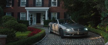 Movie still from “Every Day” (2018), directed by Michael Sucsy – A man driving a car in front of a house; Wide shot, High angle