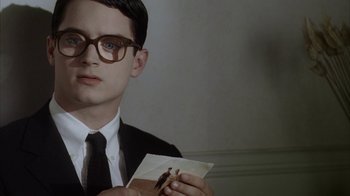 Movie still from “Everything Is Illuminated” (2005), directed by Liev Schreiber – A man in a suit and tie holding a piece of paper in front of him; Close Up shot, Over the shoulder angle