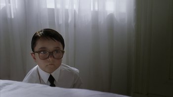 Movie still from “Everything Is Illuminated” (2005), directed by Liev Schreiber – A young boy wearing glasses and a white shirt; Medium shot, High angle