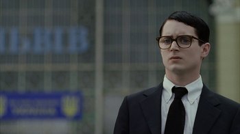 Movie still from “Everything Is Illuminated” (2005), directed by Liev Schreiber – A man in a suit and tie standing in front of a building; Close Up shot, Low angle