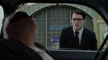 Movie still from “Everything Is Illuminated” (2005), directed by Liev Schreiber – A man in a suit and tie looking into a car mirror; Medium shot, Low angle