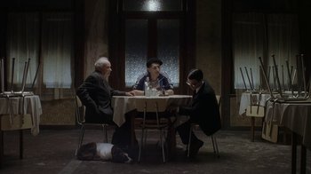 Movie still from “Everything Is Illuminated” (2005), directed by Liev Schreiber – A group of people sitting at a table with a dog; Wide shot, Over the shoulder angle