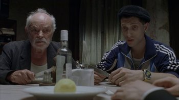 Movie still from “Everything Is Illuminated” (2005), directed by Liev Schreiber – Two men sitting at a table with a bottle of wine; Medium shot, Over the shoulder angle