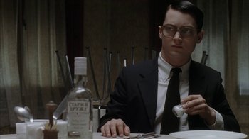 Movie still from “Everything Is Illuminated” (2005), directed by Liev Schreiber – A man sitting at a table with a bottle of alcohol; Close Up shot, Low angle