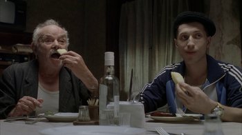 Movie still from “Everything Is Illuminated” (2005), directed by Liev Schreiber – Two people sitting at a dinner table eating food; Medium shot, Over the shoulder angle